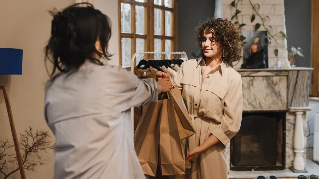 Vendedora entregando as sacolas de compra para a cliente numa loja