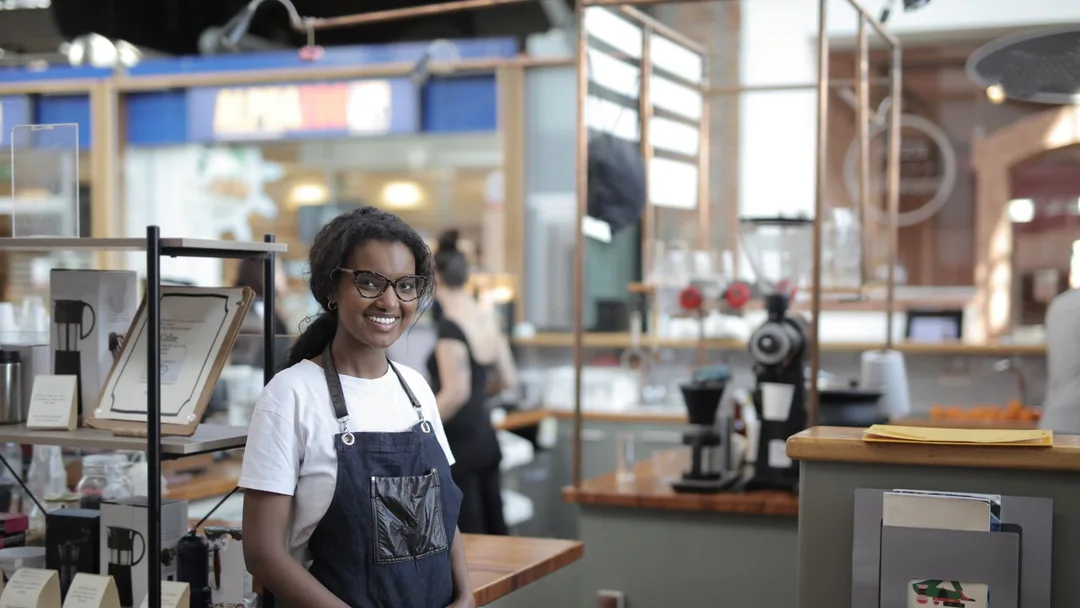 Dona de loja sorrindo no balcão de uma cafeteria