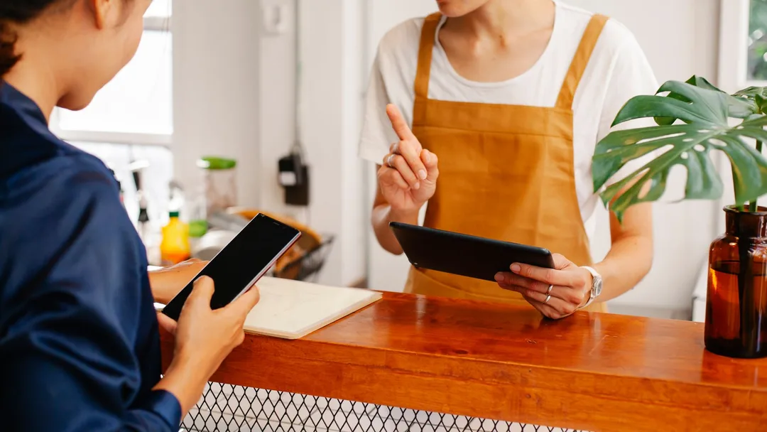 Lojista olhando números no tablet atrás do balcão
